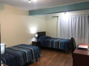 a room with two beds and a table and a desk at Gran Casa a pasos Casino ANTAY in Copiapó