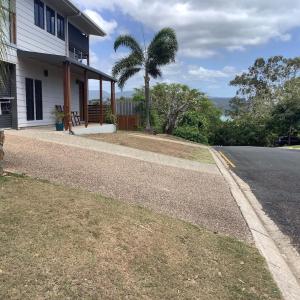 a house with a palm tree on the side of the road at Oceanview Apartment in Airlie Beach