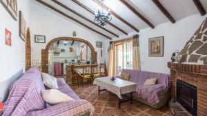 een woonkamer met 2 paarse banken en een open haard bij Casa Ameli Competa by Ruralidays in Cómpeta