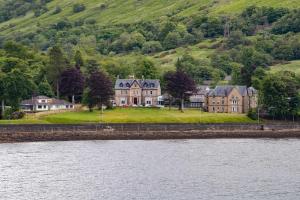 a large house on a hill next to a body of water at The Caledonian Claymore Hotel in Arrochar