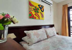 1 dormitorio con 1 cama y un jarrón de flores sobre una mesa en Água Marinha de Bombas - Bombinhas, en Bombinhas