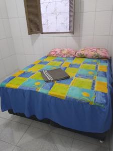 a bed with a colorful quilt on top of it at Quarto casal sossegado perto Pelourinho in Salvador