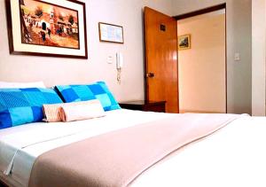 ein Schlafzimmer mit einem großen weißen Bett mit blauen Kissen in der Unterkunft HOTEL GLAMOUR in Lima
