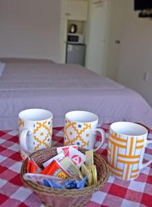 een tafel met drie koffiekopjes en een mand snoep bij Trinidad Inn Flores in Trinidad
