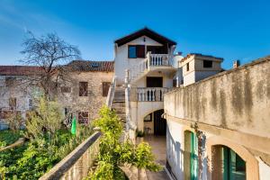an old house with a staircase in front of a wall at Apartments Land - 100m to the sea in Zlarin