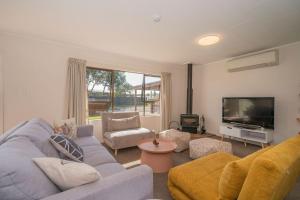 a living room with a blue couch and a tv at Hosts on the Coast Cosy on Cath in Whitianga