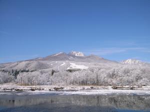 a mountain in the distance with a river and snow at Hotel Senke in Myoko