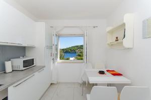eine weiße Küche mit einem Tisch und einer Mikrowelle in der Unterkunft Apartment Jakov in Rogač