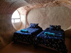 a room with two beds in a cave with a window at Underwood Court fresh Dugout- Hosted by Coober Pedy Accommodations in Coober Pedy