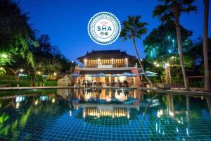 - une piscine en face d'un bâtiment la nuit dans l'établissement Sibsan Resort & Spa Maetaeng SHA, à Mae Taeng