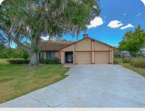 a large house with a tree in the driveway at Irises House - private room in home in Kissimmee