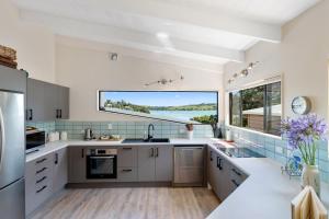 a kitchen with white cabinets and a large window at Greenslade Canopy - Raglan Holiday Home in Raglan