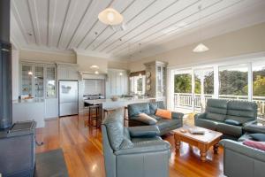 a living room with two couches and a kitchen at The Verandah - Napier Holiday Home in Onekawa