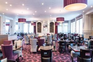 a dining room with tables and chairs and windows at The Great Western Hotel in Oban