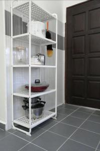 a kitchen with a white shelf with dishes on it at Simple Home by Aimie Fully Aircond in Dungun