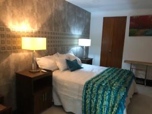 a bedroom with a bed with two lamps on it at Hotel Boutique Campanario del Río in Soledad