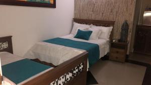 a bedroom with a bed with a green and white blanket at Hotel Boutique Campanario del Río in Soledad