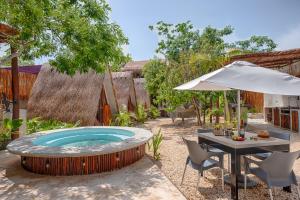 a hot tub in a yard with a table and an umbrella at aldea pukna in Akumal