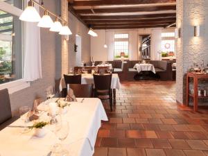 un restaurante con mesas y sillas blancas y ventanas en Hotel Haus Gimken, en Essen