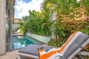 a chair next to a swimming pool in a yard at Aria Port Douglas Villas - Villa 1 in Port Douglas