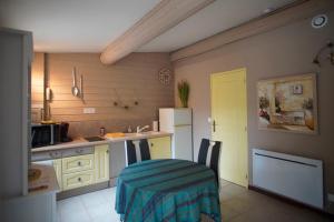 a kitchen with a table and a white refrigerator at La Pitchounette Mas Val-Chênaie Gordes in Gordes