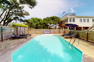 a swimming pool with two chairs and a house at Neely's Nest in Kitty Hawk