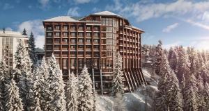 a tall building with snow covered trees in front of it at Hotel Orlovetz in Pamporovo