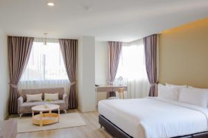 Cette chambre comprend un grand lit et une chaise. dans l'établissement The Rise Suites Hotel, Chiang Mai - SHA Extra Plus, à Chiang Mai