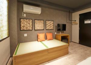 a bedroom with a bed with orange pillows on it at IKIDANE Residential Hotel Sumida Kyojima in Tokyo