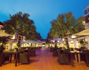 a restaurant with tables and chairs and palm trees at Village Hotel Albert Court by Far East Hospitality in Singapore