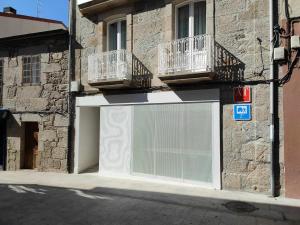 une porte de garage blanche avec 2 balcons dans un bâtiment dans l'établissement A Pousa do Asma, à Chantada
