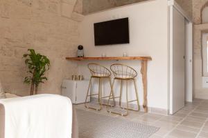 sala de estar con 2 taburetes y TV en Vico Monte II - Casa Vacanze, en Ceglie Messapica