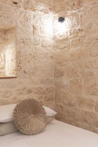 Vico Monte II - Casa Vacanze في سيغلي ميسابيكا: غرفة بحائط حجري ومخدة على سرير