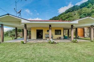 a yellow house with columns and a grass yard at Casita El Sastre in Paso Macho