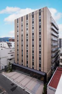 松本的住宿－Tabino Hotel lit Matsumoto，一座高大的棕褐色建筑,上面有标志