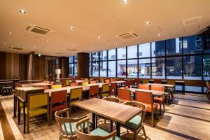 un restaurante con mesas, sillas y ventanas grandes en Tabino Hotel lit Matsumoto, en Matsumoto
