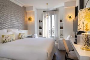 um quarto com uma grande cama branca e uma secretária em Hôtel de Banville em Paris