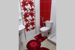 a bathroom with a toilet and red flowers on the wall at Private House with Garden and terrace in Aswan in Aswan +37 photos