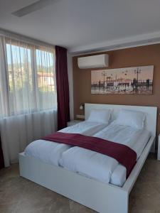 una camera da letto con un grande letto bianco di fronte a una finestra di Stella Guesthouse a Sapareva Banya