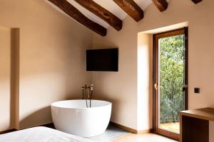 a large white tub in a room with a window at Hotel Montrubí 1771 - Slow Winery Hotel - Adults only in Font-Rubí