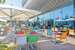 a patio with colorful chairs and tables and umbrellas at Holiday Inn Bern Westside by IHG in Bern