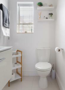 a white bathroom with a toilet and a window at 18 Abbotsford in Cape Town