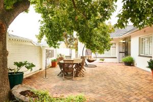 a patio with a table and chairs under a tree at 18 Abbotsford in Cape Town