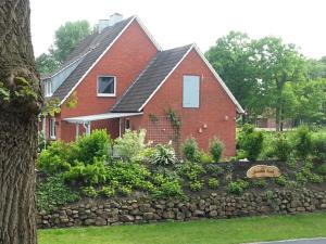 a red brick house with a stone wall at Ferienhaus Emstal in Oberlangen in Lathen