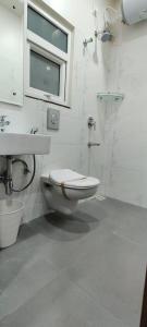 Baño blanco con aseo y lavamanos en SwanSuites Gachibowli, en Hyderabad