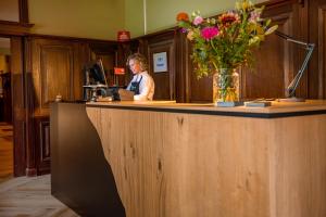 マルケローにあるLandhuis Hotel de Herikerbergの花瓶を持つカウンターに座る女性