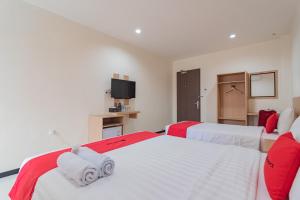 a bedroom with two beds and a tv at RedDoorz Syariah Plus near Tanjungpura University 2 Pontianak in Siantan