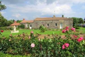 an old stone house with flowers in front of it at Maison spacieuse proche du centre de Landevieille + jardin clôturé in Landevieille