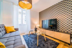 a living room with a couch and a tv at Le Contemporain - 1 Chambre in Brive-la-Gaillarde