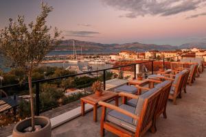 a row of tables and chairs on a balcony with a harbor at Hotel Osam - Adults Only in Supetar